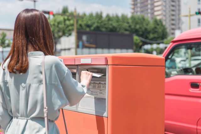 郵便ポストに投函する女性