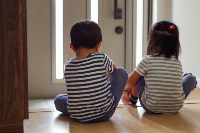 玄関で靴を履く男の子と女の子