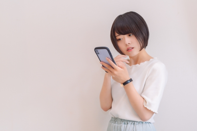 スマホを見て首をかしげる女性