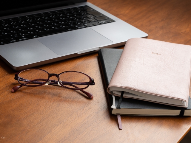 パソコンの前のノートとメガネ